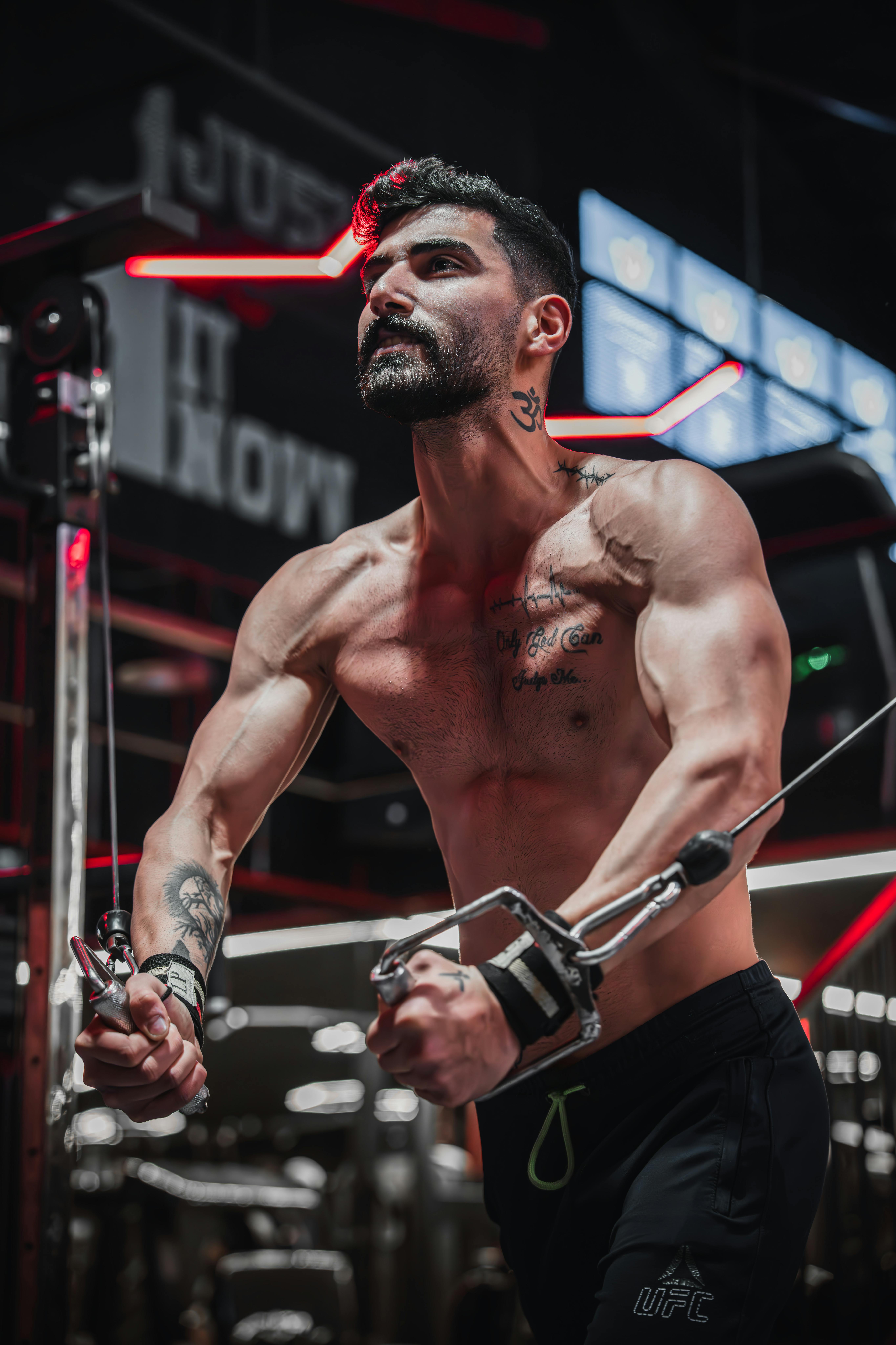Muscular man exercising on cable machine in modern gym.