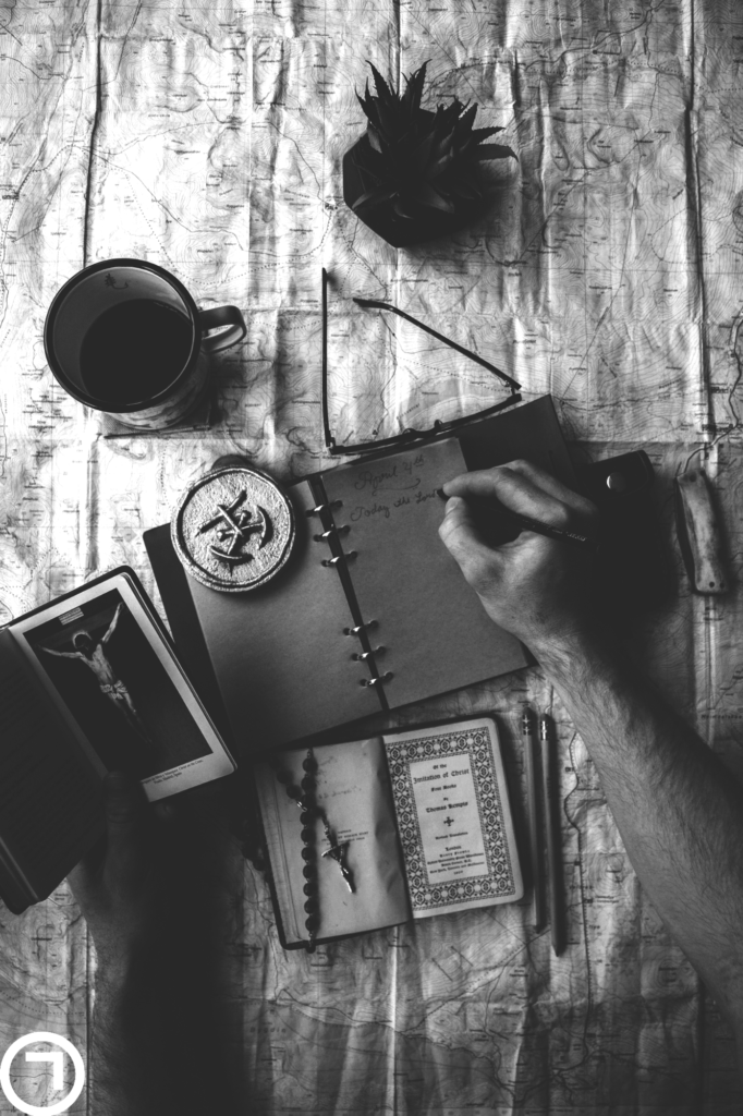 man writing journal on notebook with coffee and map setup