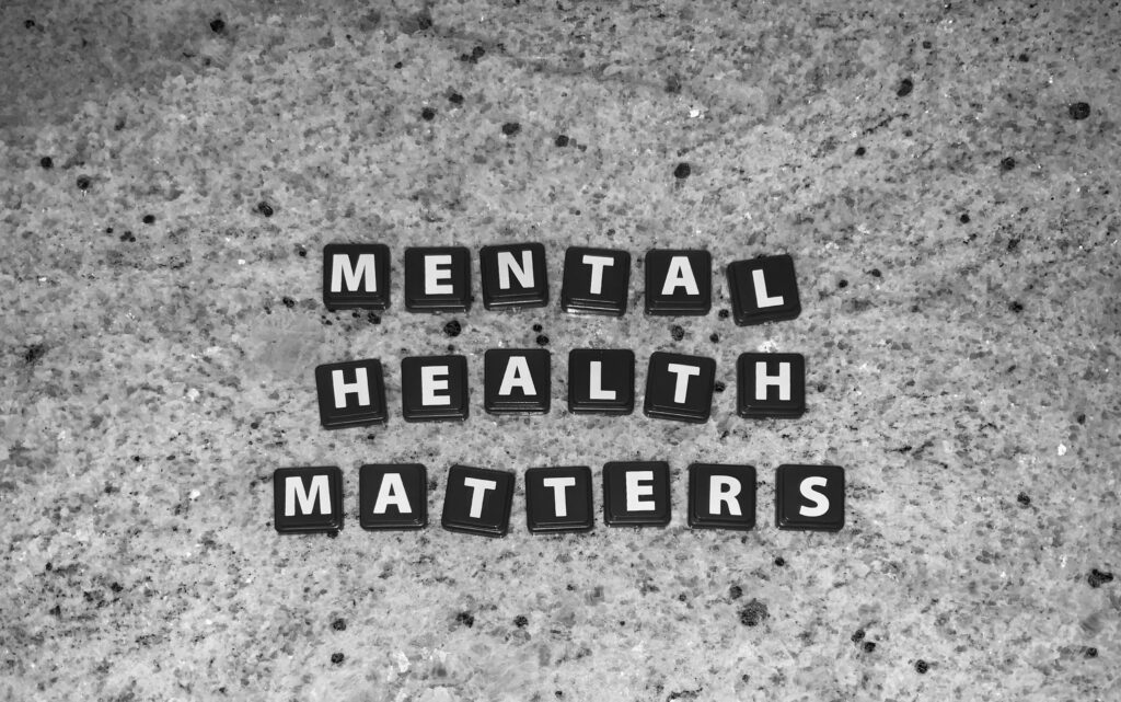 Black tiles spelling “Mental Health Matters” arranged on a textured grey surface.