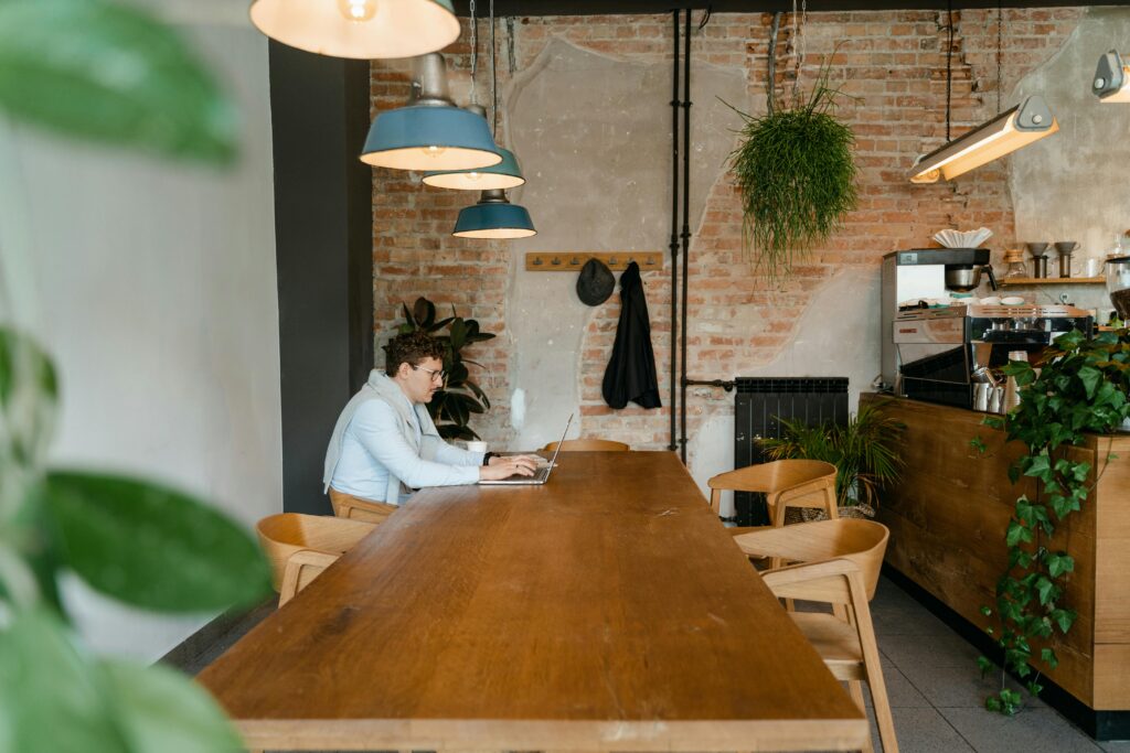 A man is working on a laptop in a cafe.