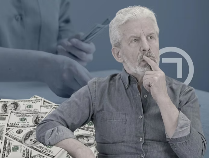 A thoughtful, grey-haired man in a denim shirt sits in contemplation, with a pile of $100 bills in the foreground. In the blurred background, a hand holds more currency, symbolizing financial planning, wealth management, and strategic life decisions for men.