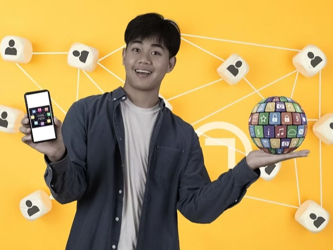 A confident young man in a denim shirt holding a smartphone in one hand and a digital globe composed of various app icons in the other. The background features a vibrant yellow color with a network of "user" icons, symbolizing connectivity and the power of mobile technology in a man's daily life.