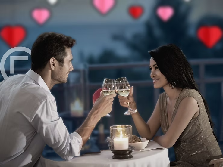a man and a woman are toasting while smiling at each other.