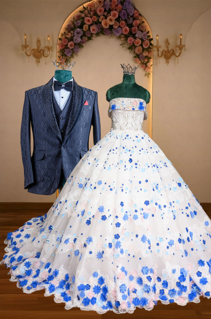 White bridal ball gown adorned with blue floral appliqués paired with a dark navy patterned tuxedo, blending romance and modern elegance.